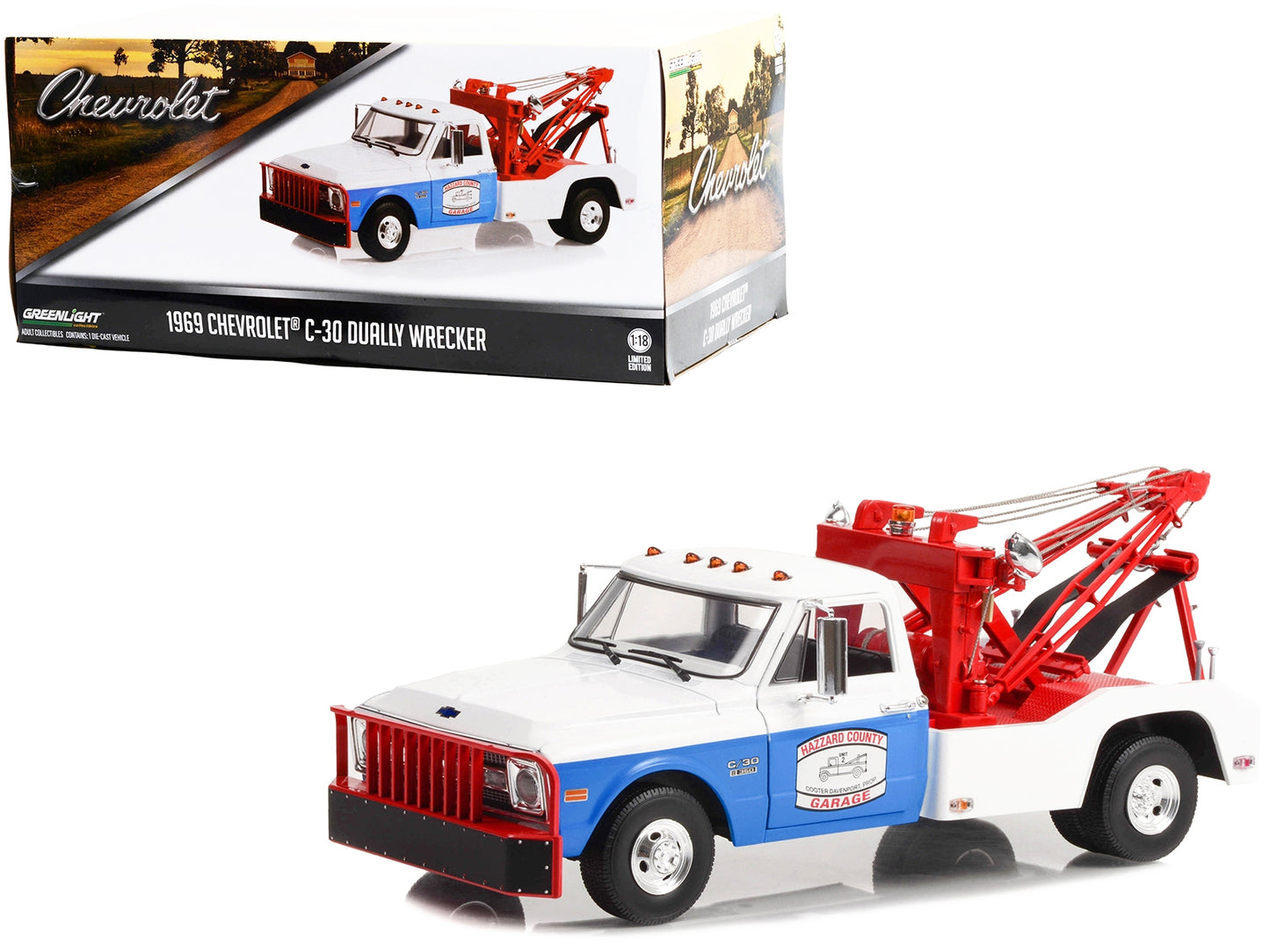 White and blue 1/18 diecast Chevrolet C-30 dually wrecker tow truck model by Greenlight with "Hazzard County Garage" branding.