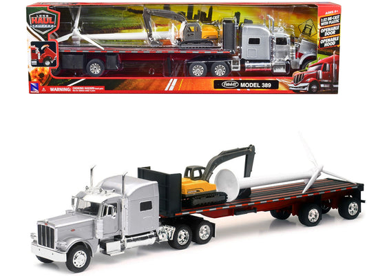Silver metallic Peterbilt 389 truck with flatbed trailer, excavator, and wind turbine diecast model by New Ray.