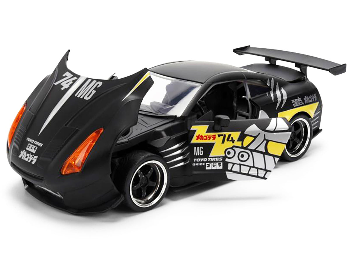 2009 Nissan GT-R R35 diecast model car by Jada, black with "Mechagodzilla" graphics, part of Hollywood Rides series, American Smart brand.