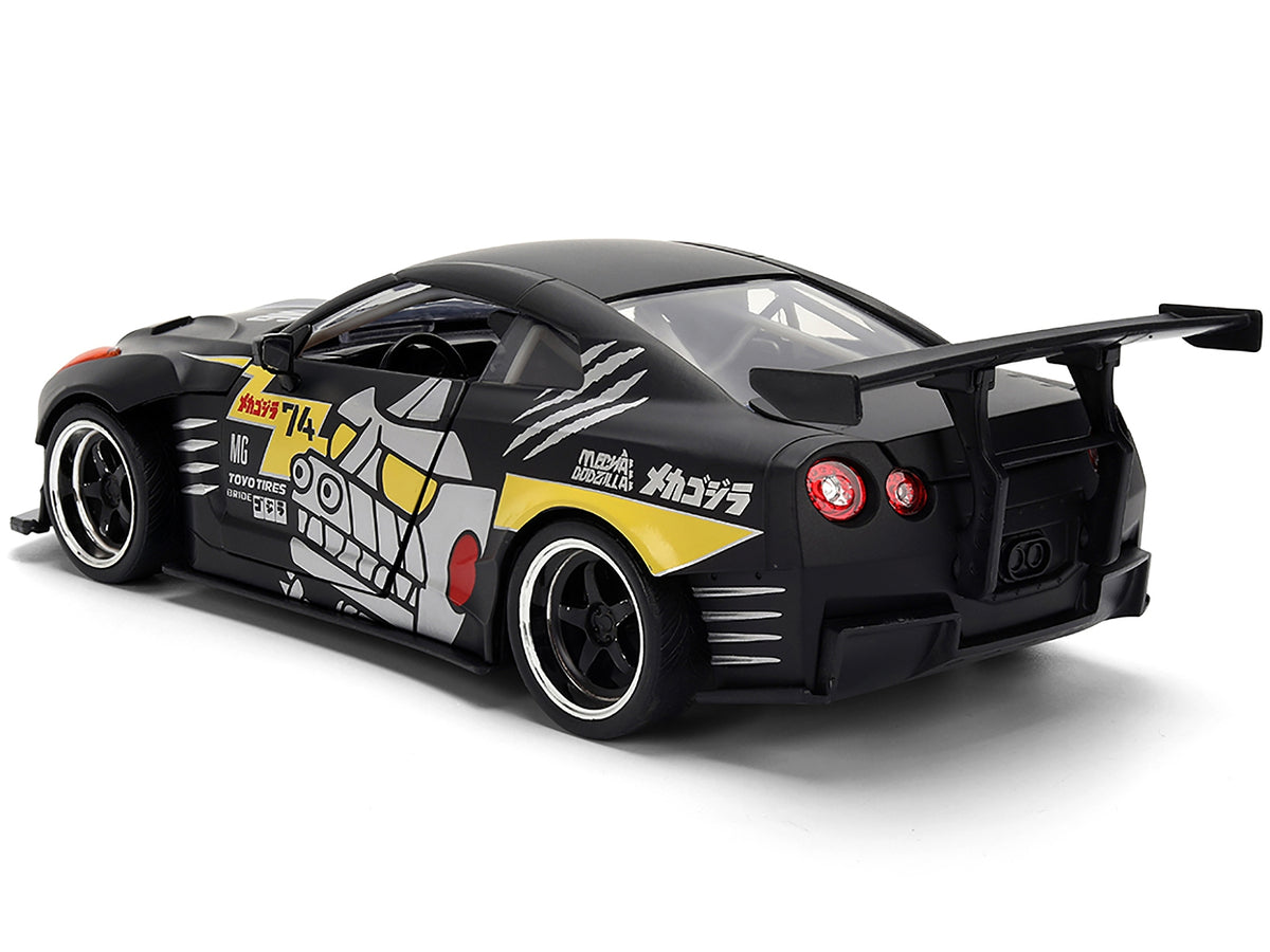 2009 Nissan GT-R R35 diecast model car by Jada in matte black with "Mechagodzilla" graphics from Hollywood Rides series, 1/24 scale.