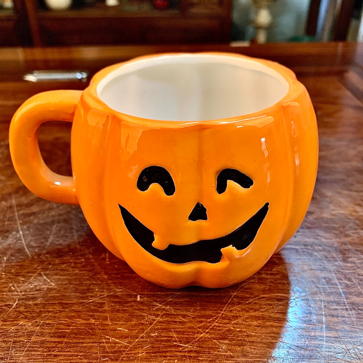 Ceramic Halloween pumpkin mug by ClaudiaG Home featuring a festive orange pumpkin design with a handle and spooky face.