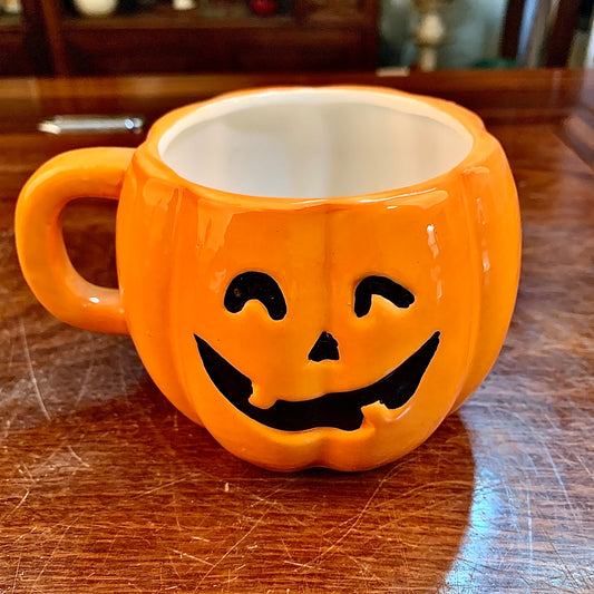 Ceramic Halloween pumpkin mug by ClaudiaG Home featuring a festive orange pumpkin design with a handle and spooky face.